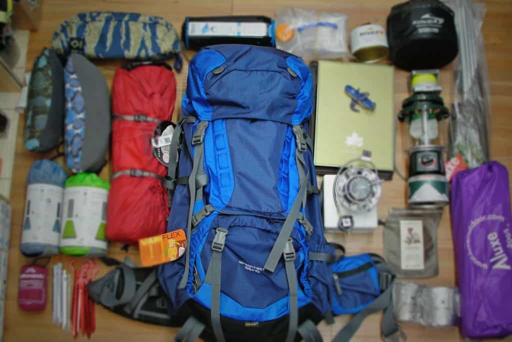 A large camping backpack sitting on top of a wooden floor.