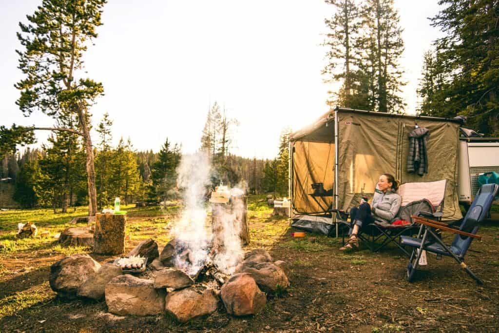 a man sitting in a chair next to a campfire.