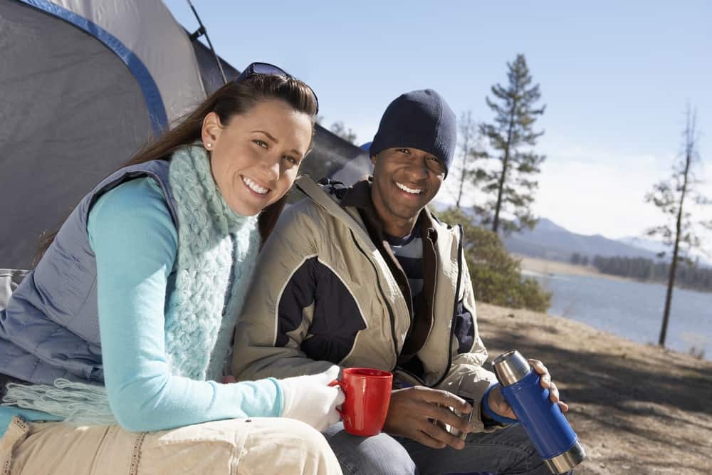 Camping in winter A man and woman sitting in front of a tent.